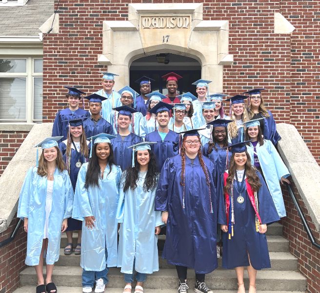  About two dozen seniors in caps and gowns on steps of Madison Elementary 